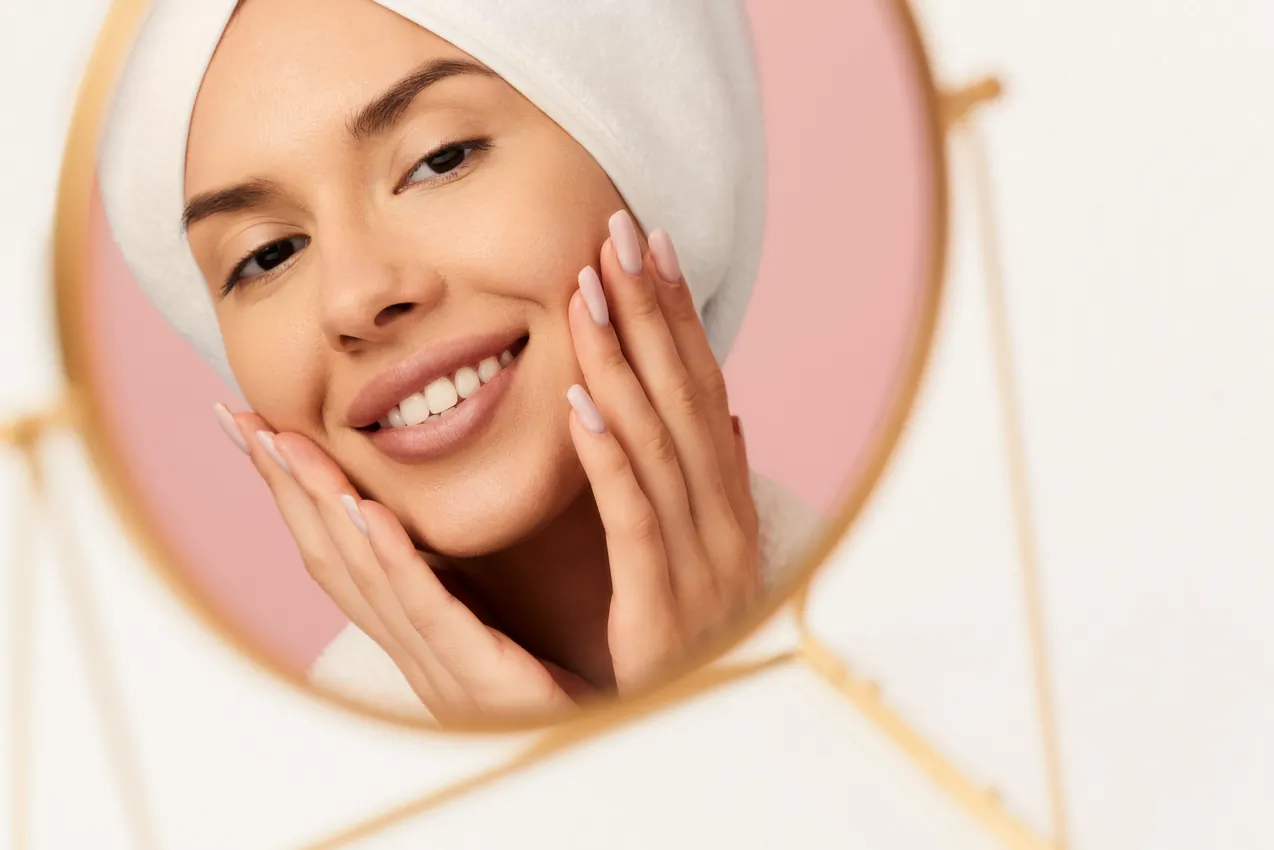 10 نصائح لاستعادة نضارة البشرة الطبيعية بسرعة 3 young woman looking in the mirror doing skincare